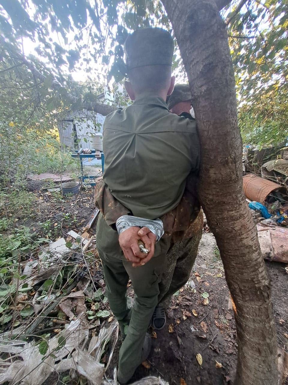 Двое военнопленных, один из которых вынужден держать гранату с выдернутой чекой